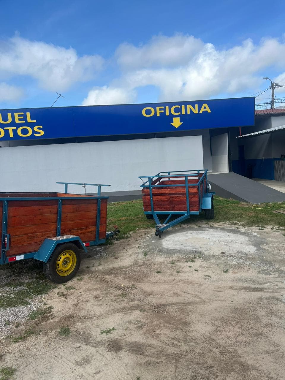 Duas carretinhas novas de caçamba de madeira no pátio, em frente à loja